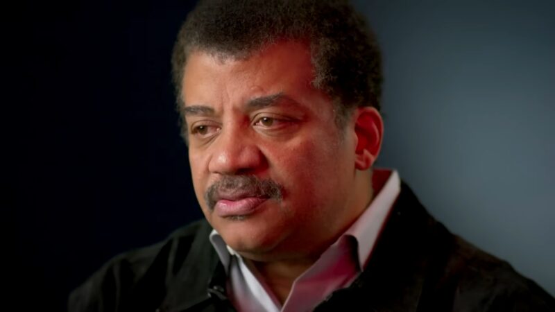 Neil deGrasse Tyson during an interview with a dark background and focused expression
