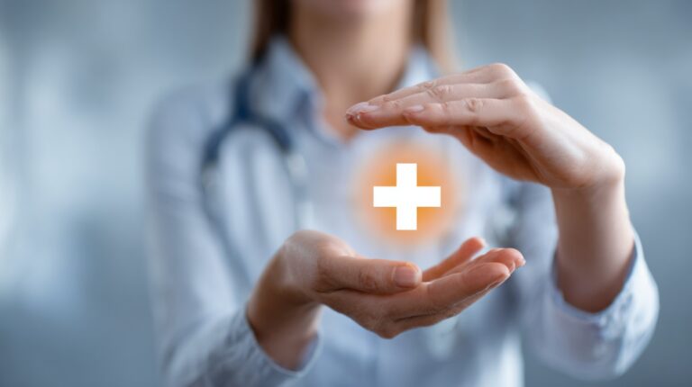 Doctor holding hands around a glowing medical cross symbol