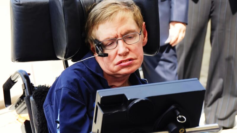 Stephen Hawking in a wheelchair using a speech device during a public appearance