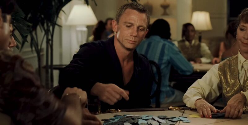 Male actor seated at a casino table during a film scene.