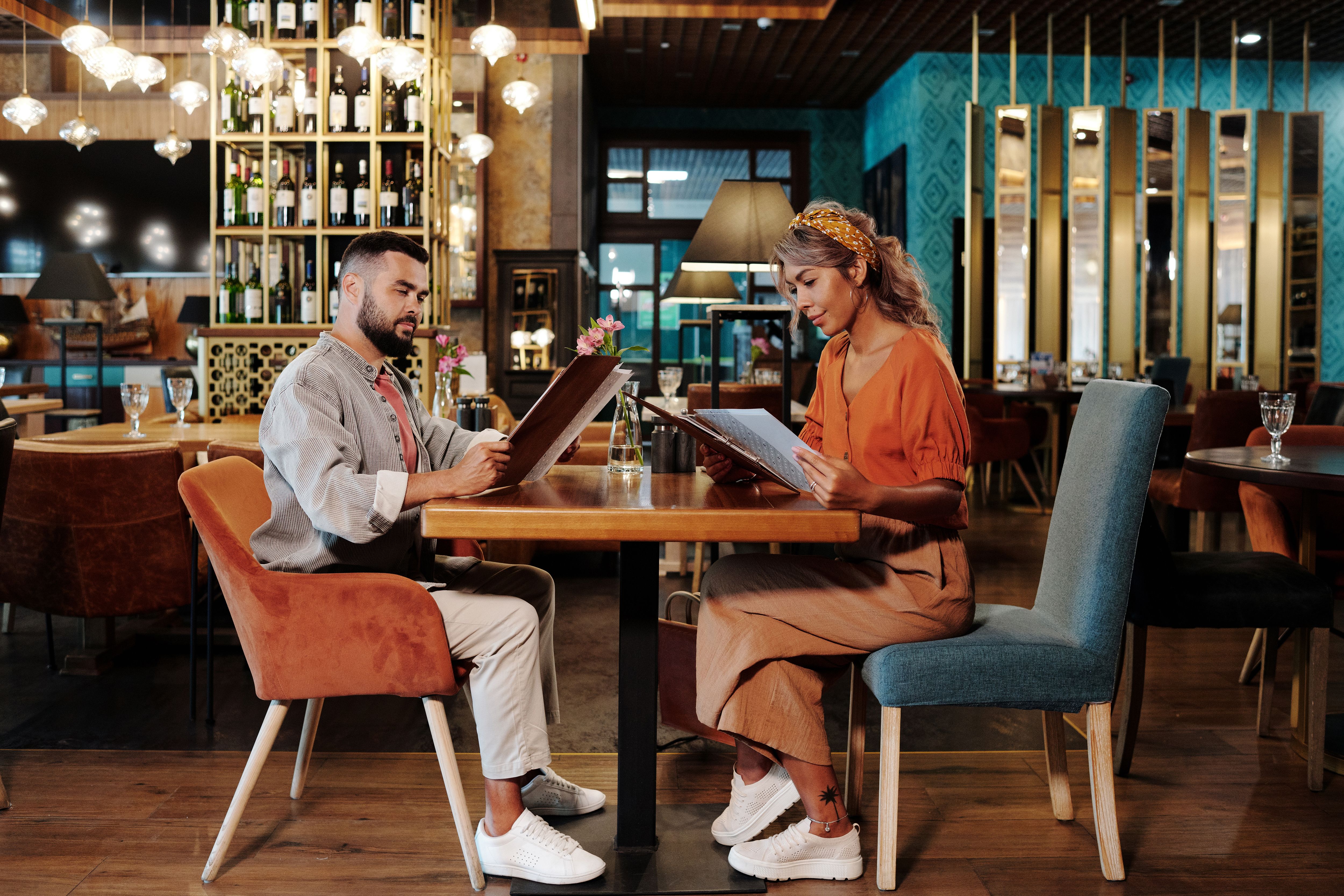 A couple reviewing a menu together at a restaurant, illustrating companionship during a dinner outing.