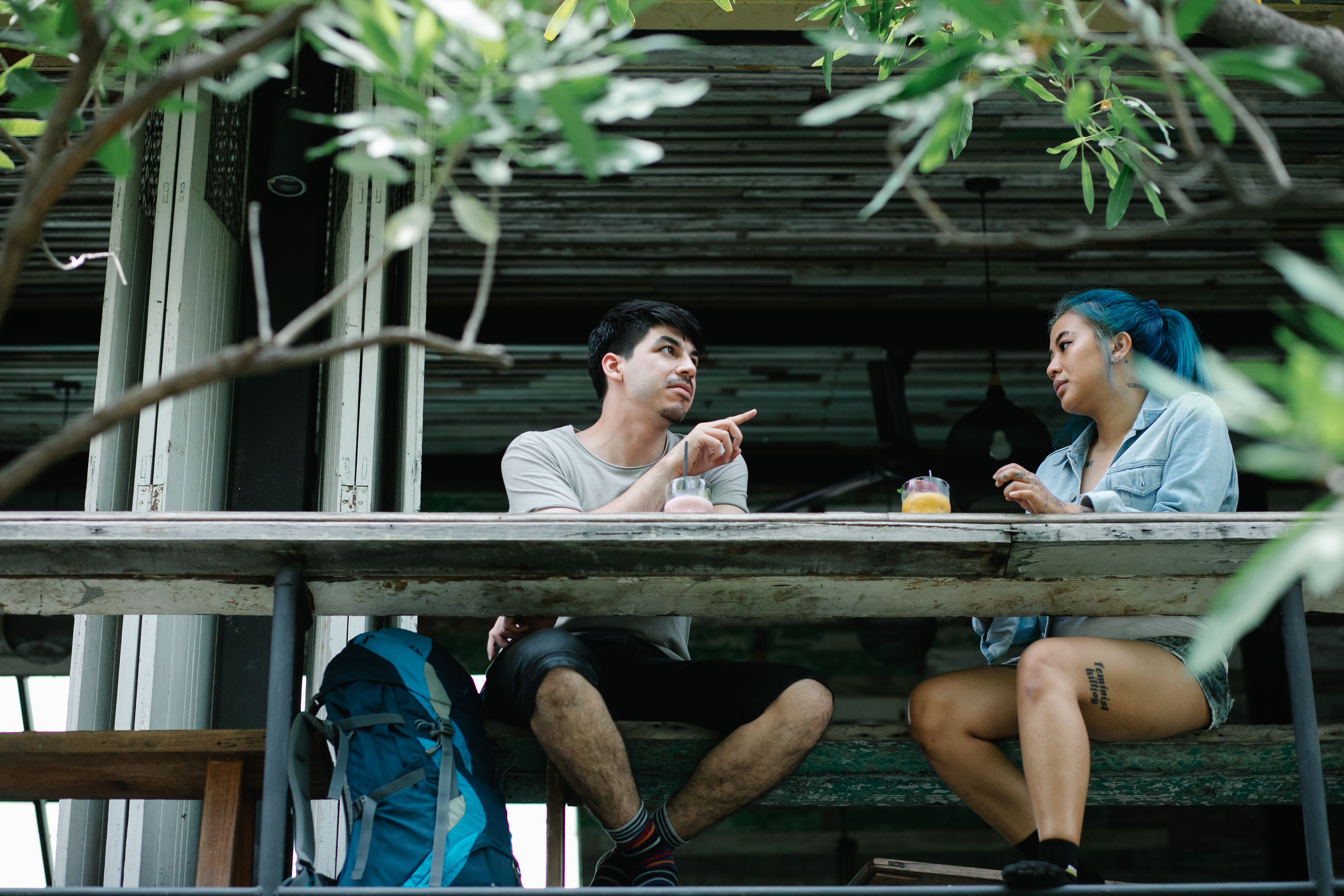 A woman and man talking over drinks at an outdoor café, suggesting an easygoing companionship outing.